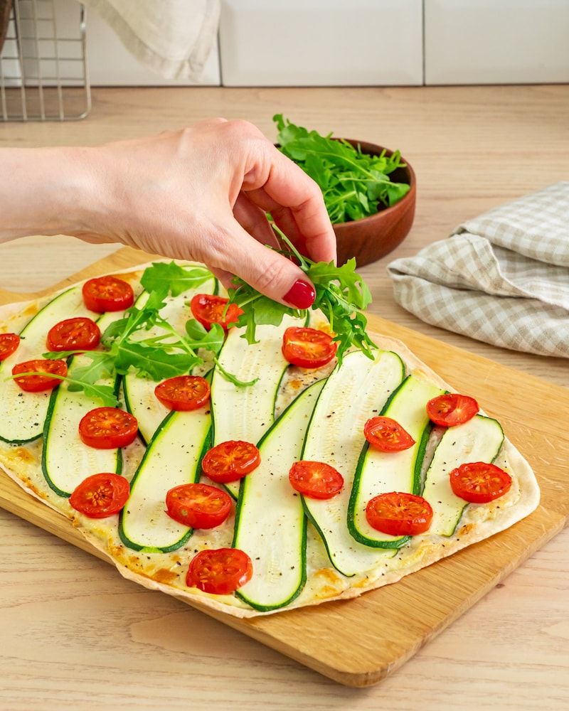 Dieses Bild zeigt der Flammkuchen belegt wird.