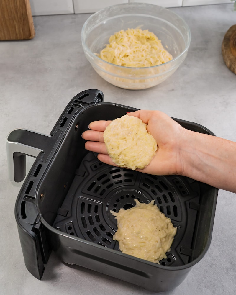 Diese Bild zeigt wie Kartoffelmasse in den Garkorb der Heißluftfritteuse gegeben wird.
