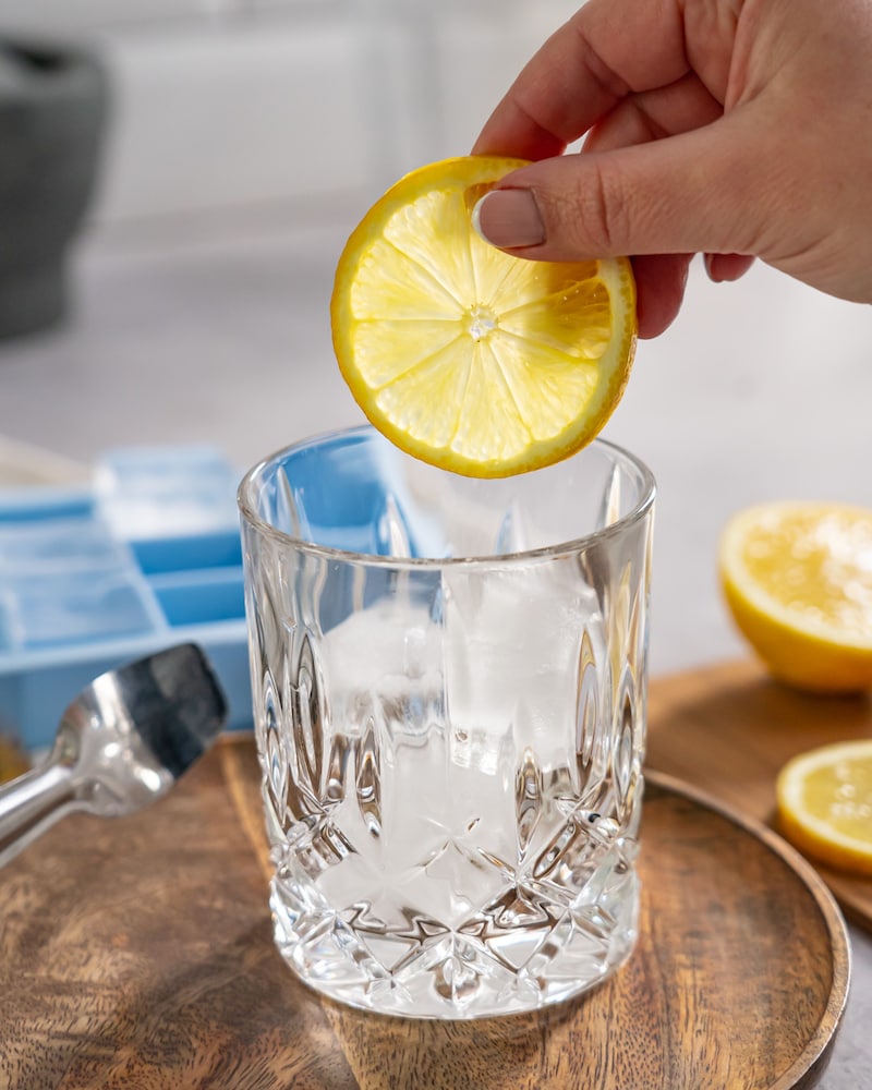Dieses Bild zeigt wie eine Zitronenscheibe ins Glas gegeben wird.