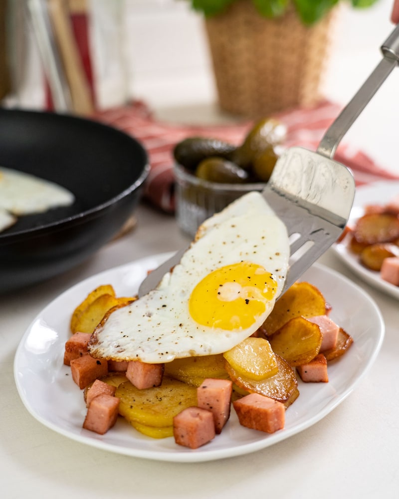 Auf diesem Bild siehst du wie ein Spiegelei auf die Bratkartoffeln gegeben wird.