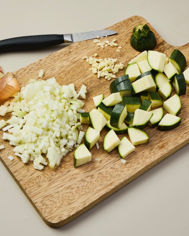Dieses Bild zeigt wie die Zwiebeln und Zucchini kleingeschnitten werden.