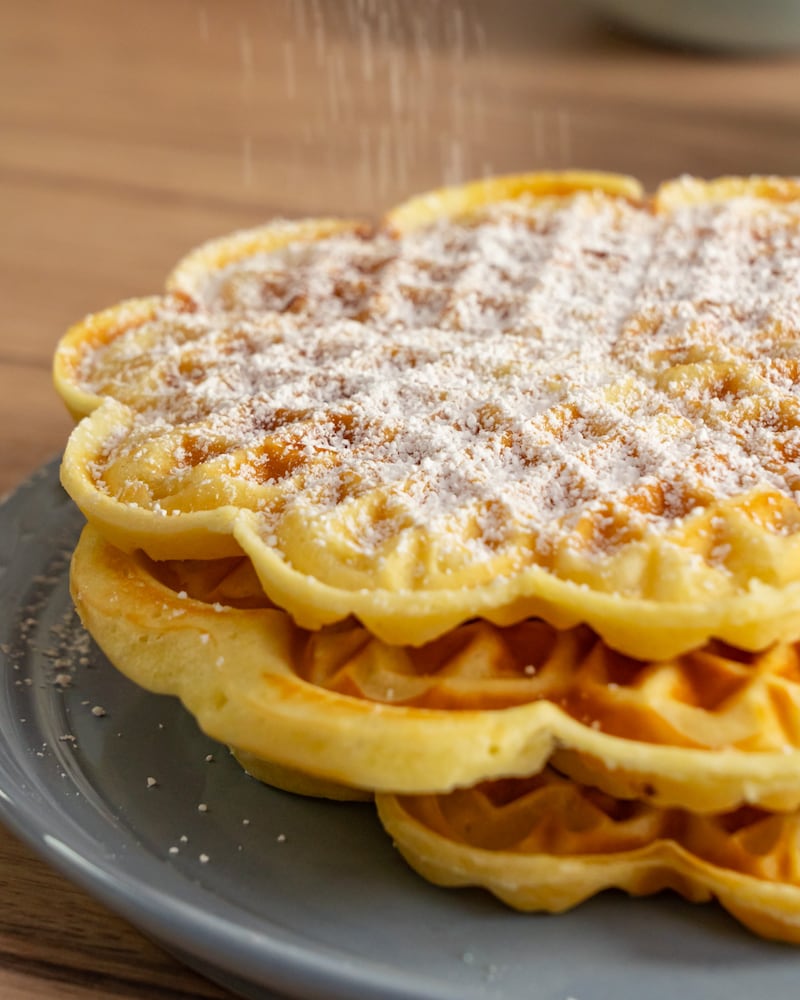 Dieses Bild zeigt wie der Puderzucker über die Waffelen gegeben wird.