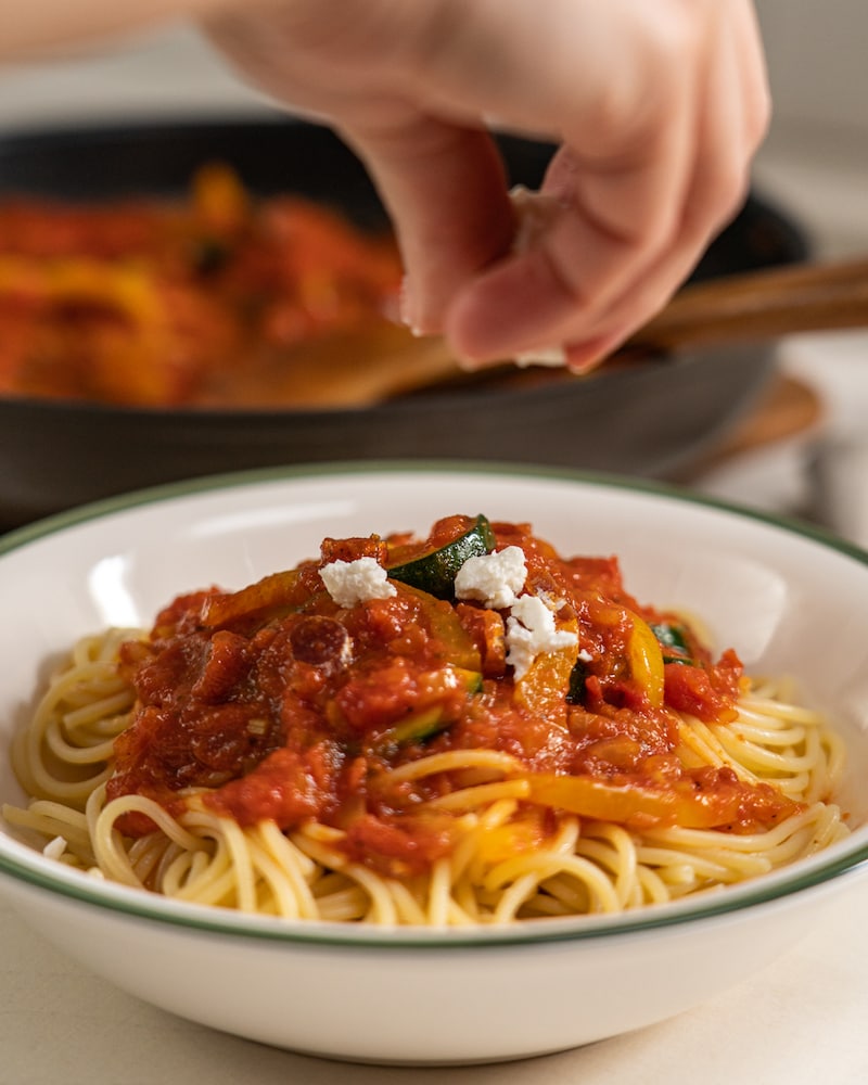 Auf diesem Bild siehst du wie Feta über die Spaghetti gestrudelt wird.