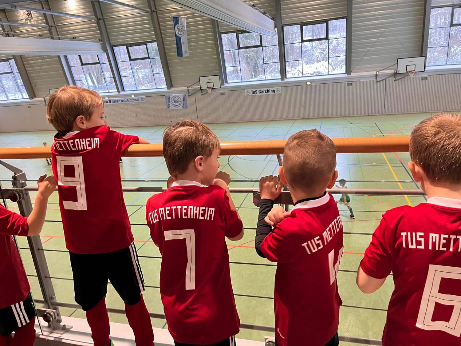 Kinder blicken von einer Tribuene auf ein Spielfeld