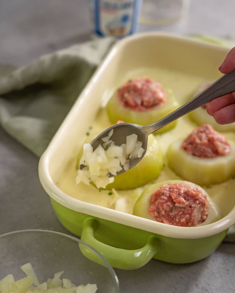 Dieses Bild zeigt wie Zwiebeln in die Auflaufform gegeben werden.