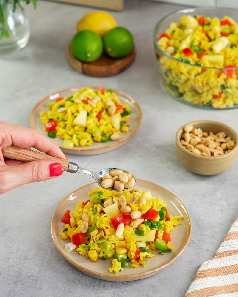 Dieses Bild zeigt wie der Salat mit Erdnüssen bestreut wird.
