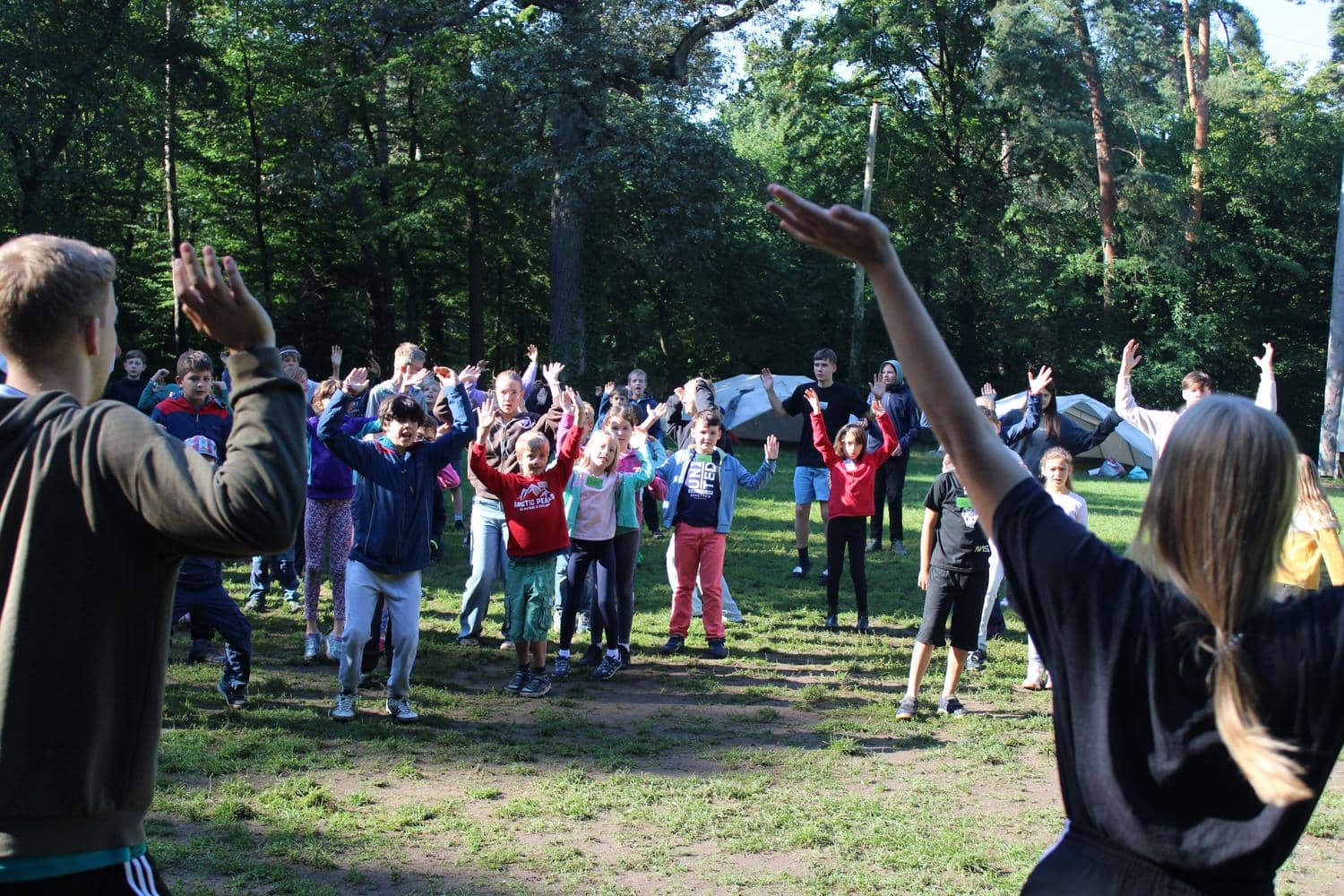 Kinder tanzen auf dem Zeltlager im Gruenen