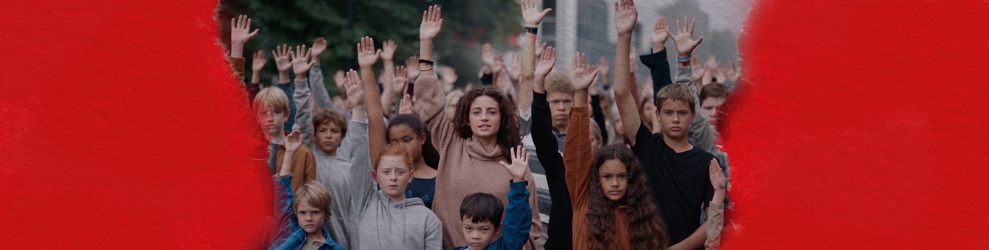 Mehrere Kinder stehen gemeinsam auf der Straße und strecken eine Hand nach oben. Ihre Gesichter sind ernst und entschlossen. 