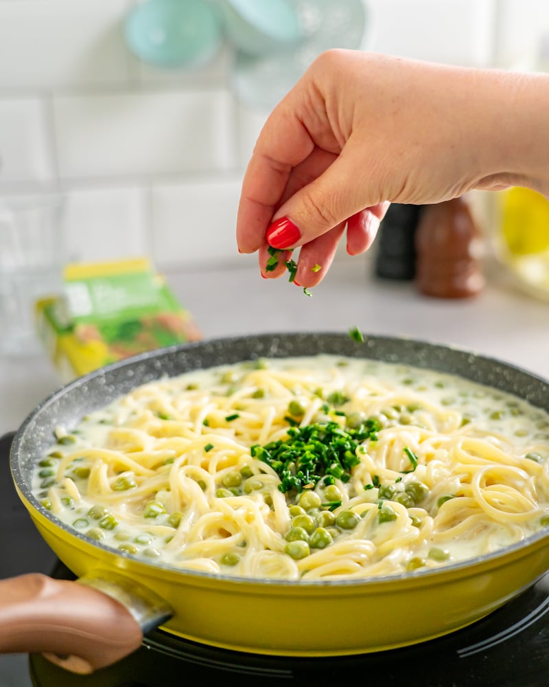 Dieses Bild zeigt wie der Schnittlauch zur Pasta hinzugegeben wird.