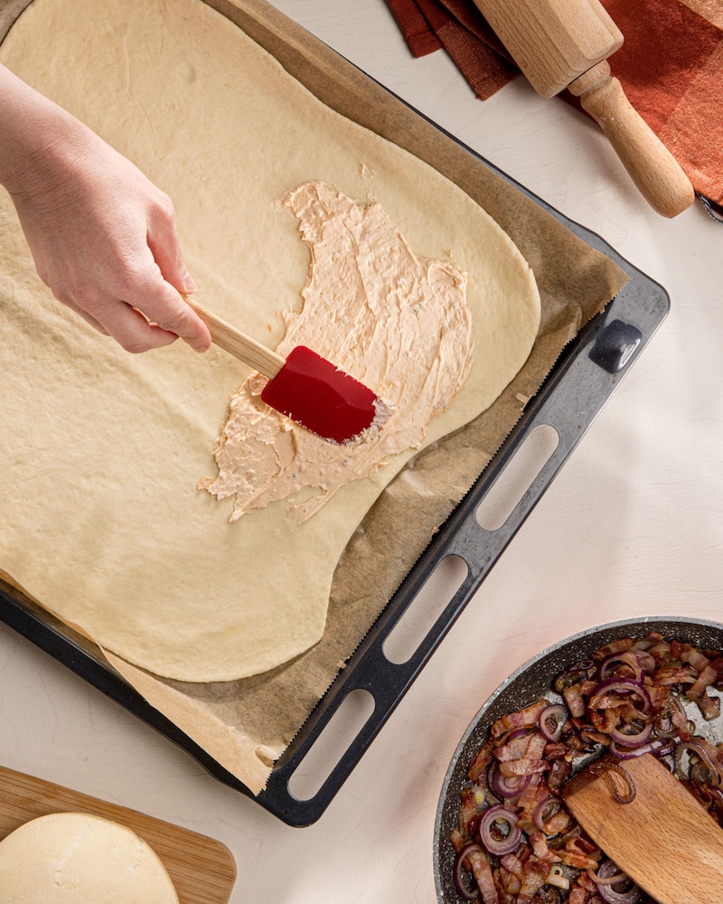 Dieses Bild zeigt wie der Teig mit Frischkäse bestrichen wird.