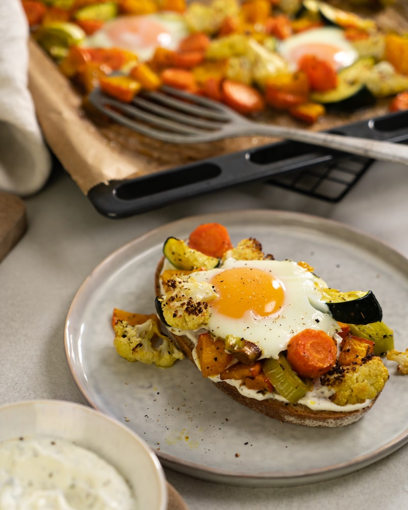 Auf diesem Bild siehst du unser buntes Ofengemüse mit Ei auf einer Scheibe Brot.