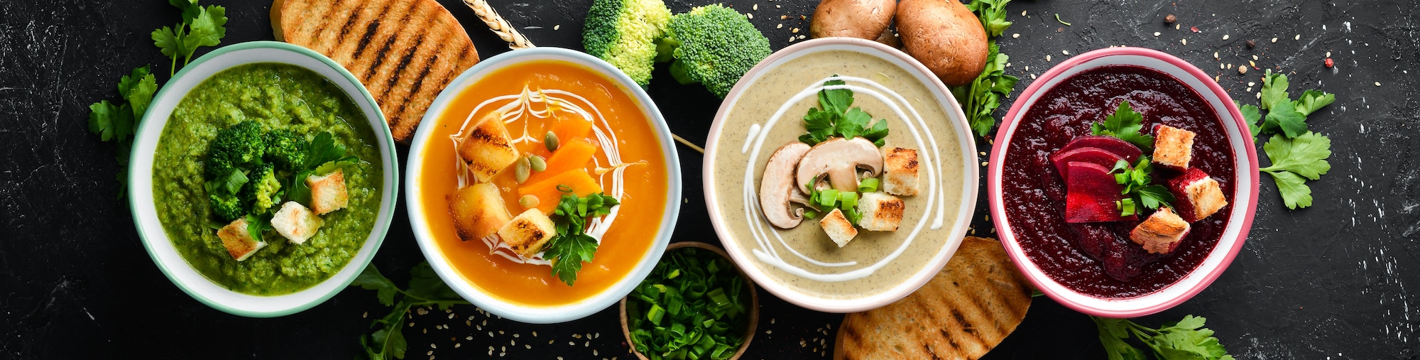 4 Schälchen mit Suppen auf dunklem Grund