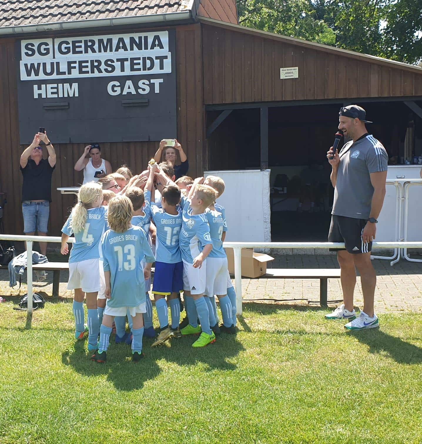 Kinder auf dem Spielfeld rufen froehlich ihren Schlachtruf