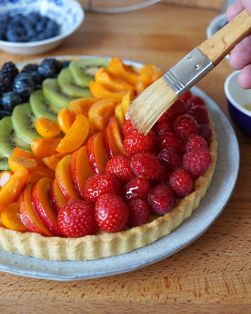 Dieses Bild zeigt wie der Tortenguss über das Obst gepinselt wird.