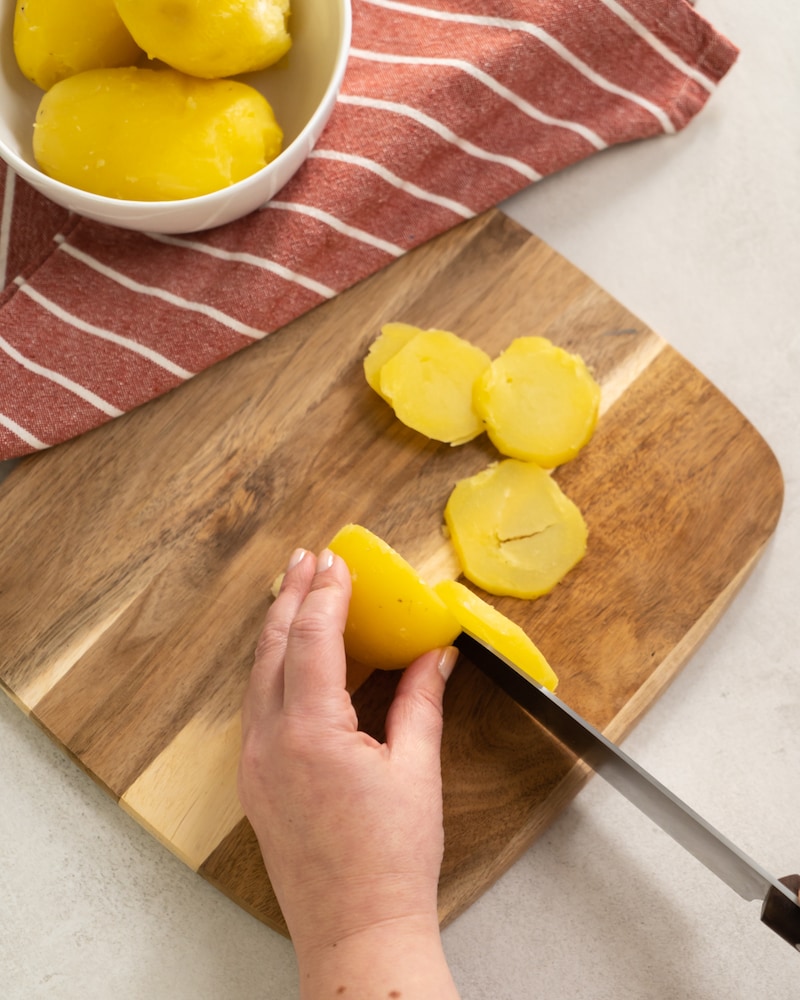 Auf diesem Bild siehst du wie Kartoffeln in Scheiben geschnitten werden.