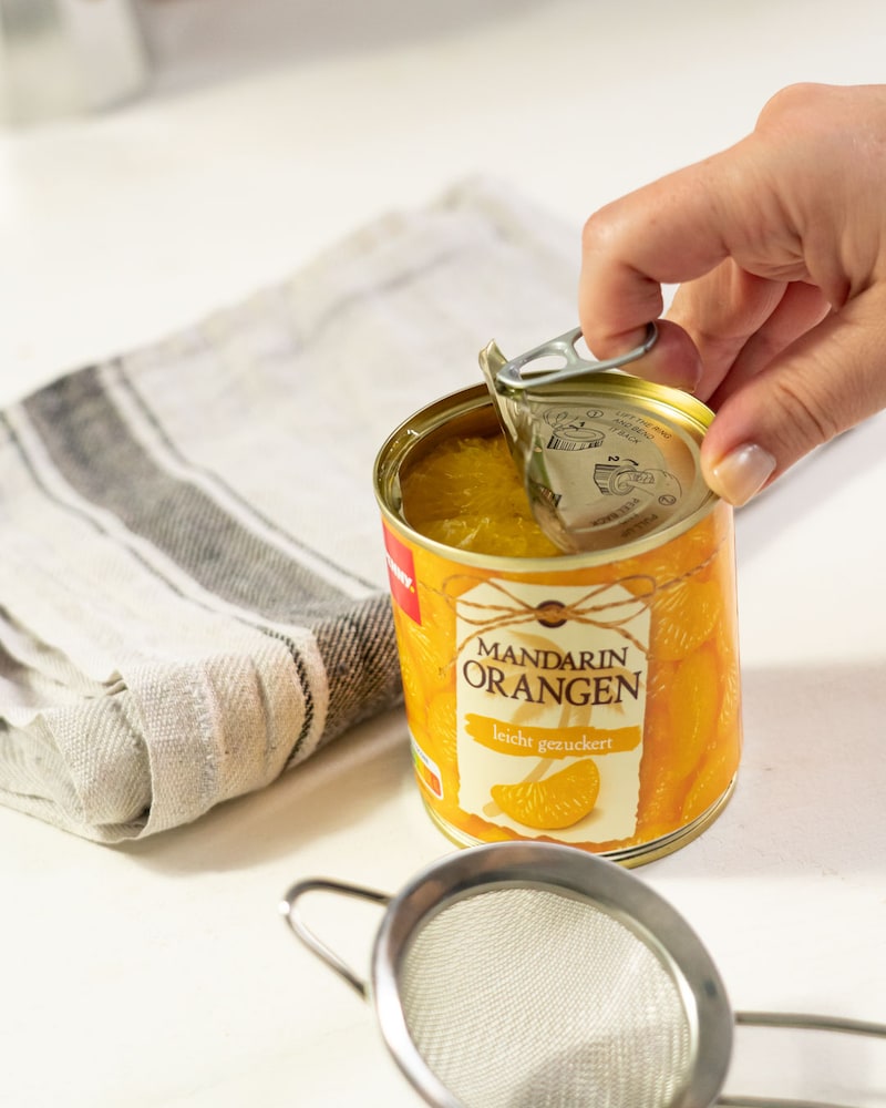 Dieses Bild zeigt wie Dosen Mandarinen geöffnet werden.