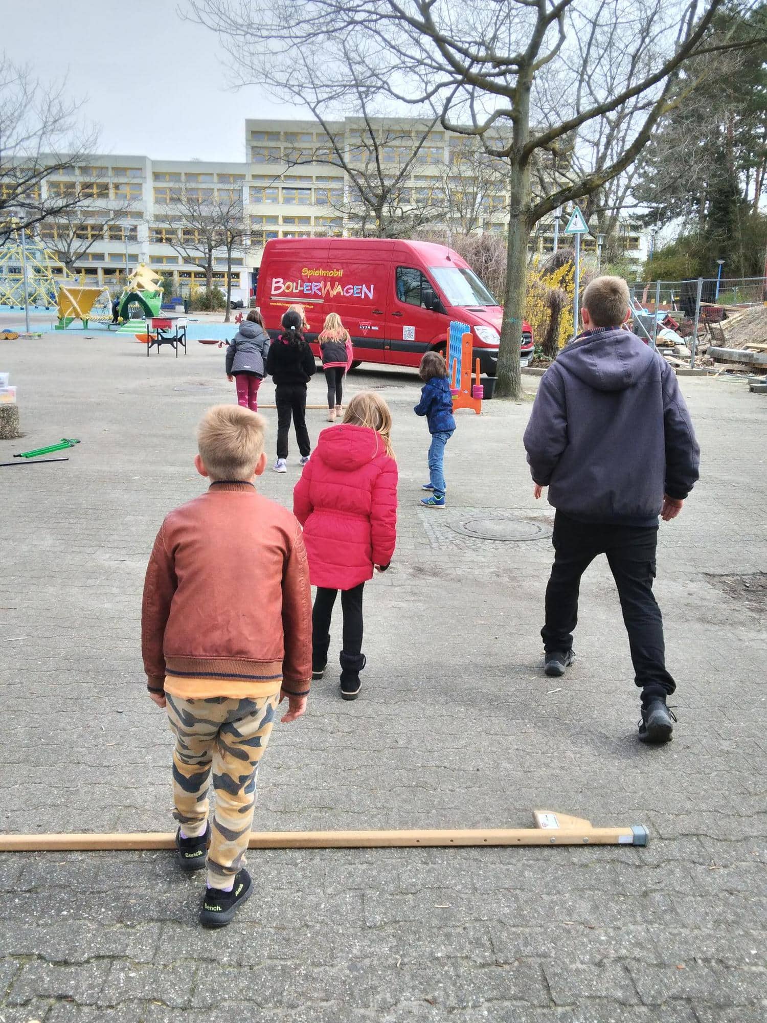 Kinder rennen auf einem Spielplatz auf das Spielmobil zu