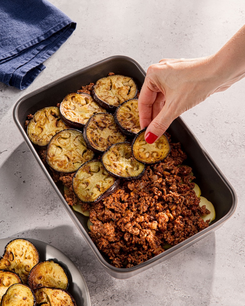 Auf diesem Bild siehst du die griechische Moussaka geschichtet wird.