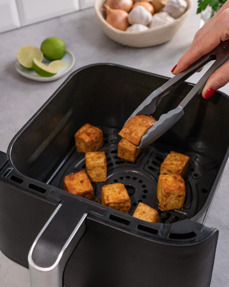 Dieses Bild zeigt wie der Tofu aus dem Airfryer geholt wird.