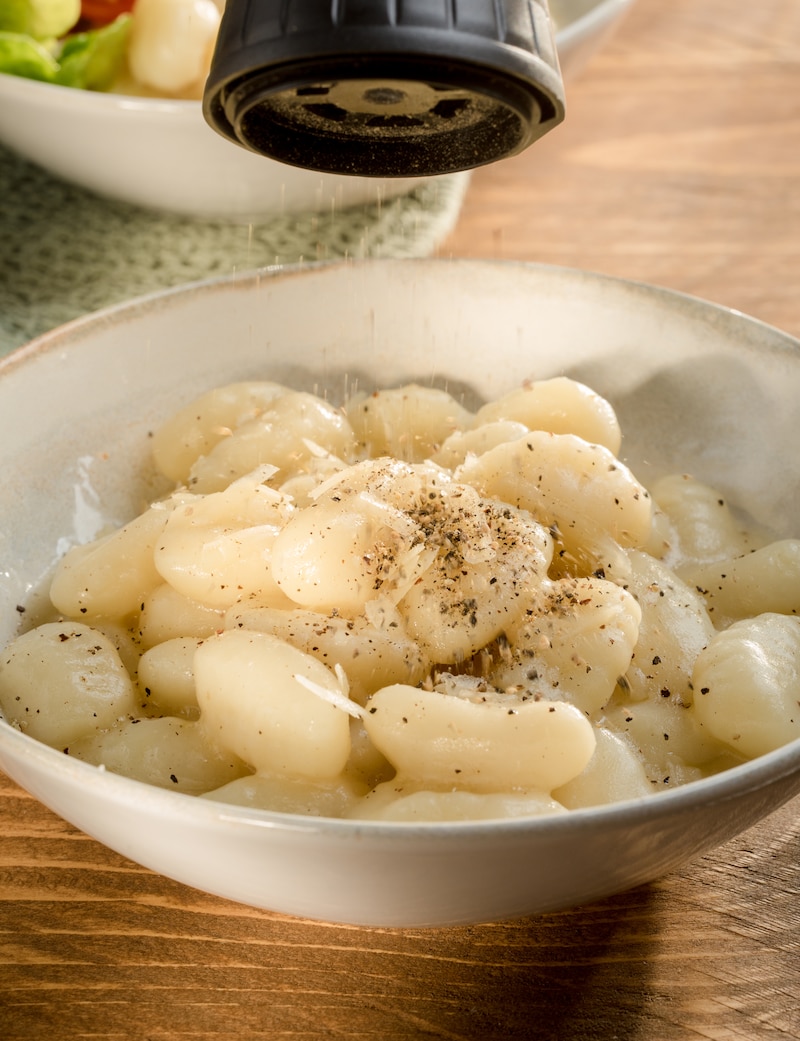 Auf diesem Bild siehst du wie Gnocchi gewürzt werden.