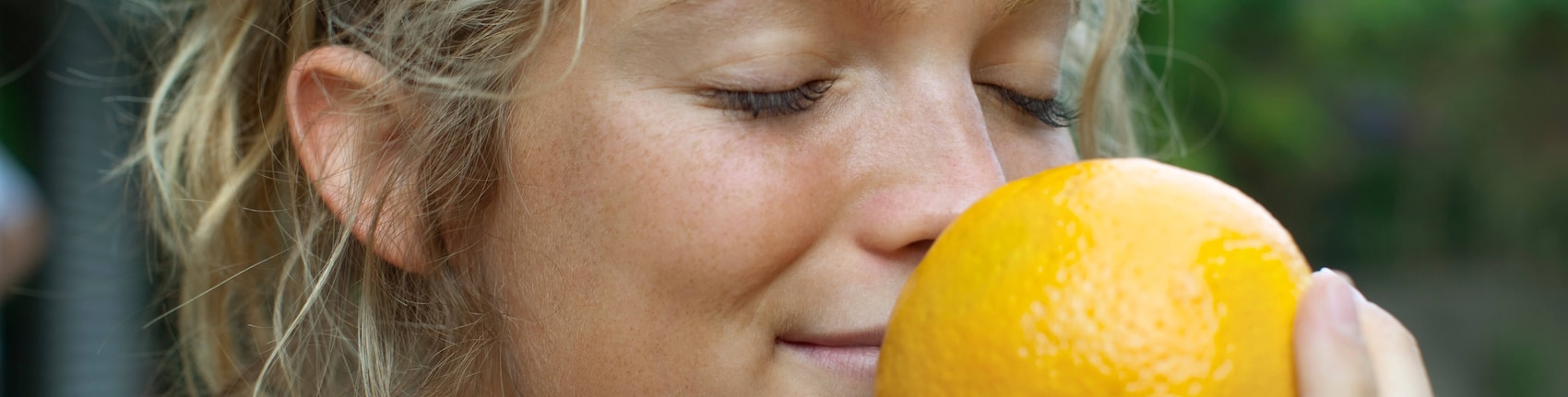 Eine Frau riecht an einer Orange