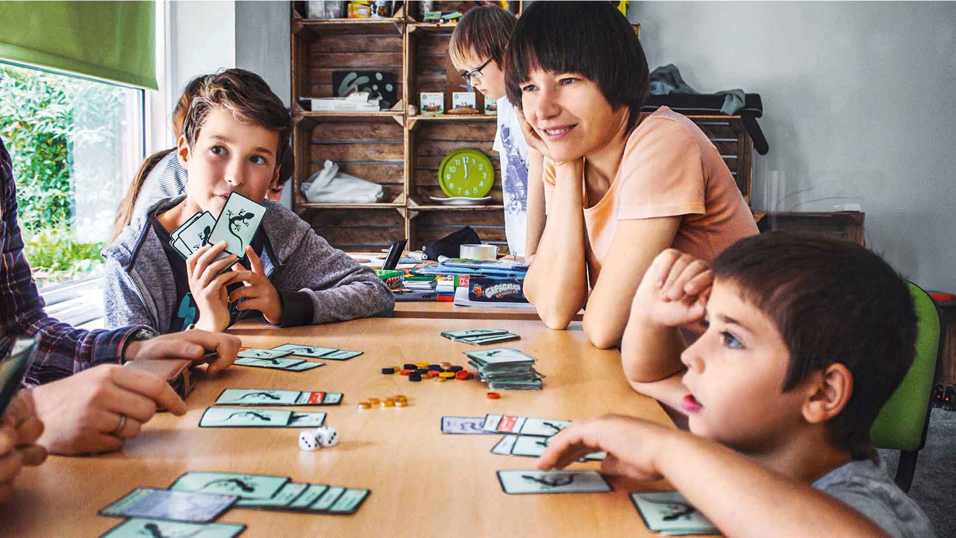Kinder und eine Erzieherin beim Spielen am Tisch