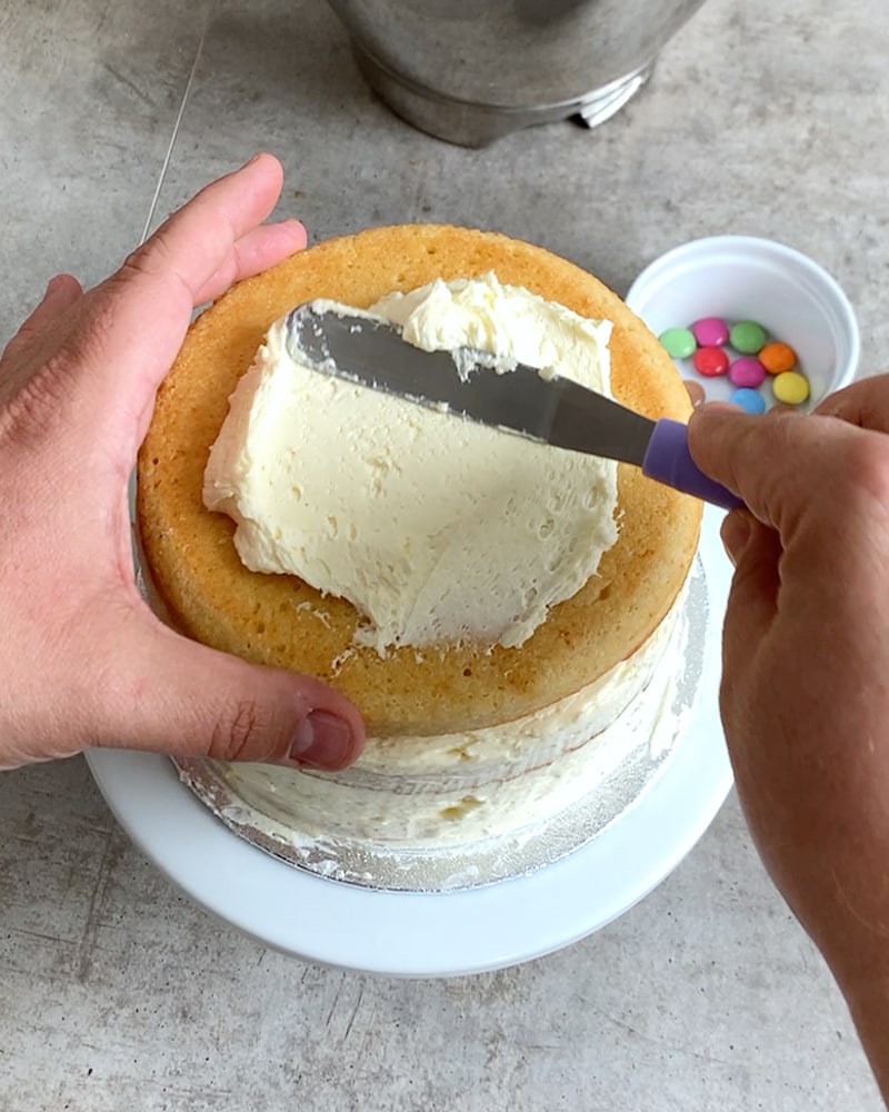 Dieses Bild zeigt wie der Kuchen mit Buttercreme bestrichen wird.