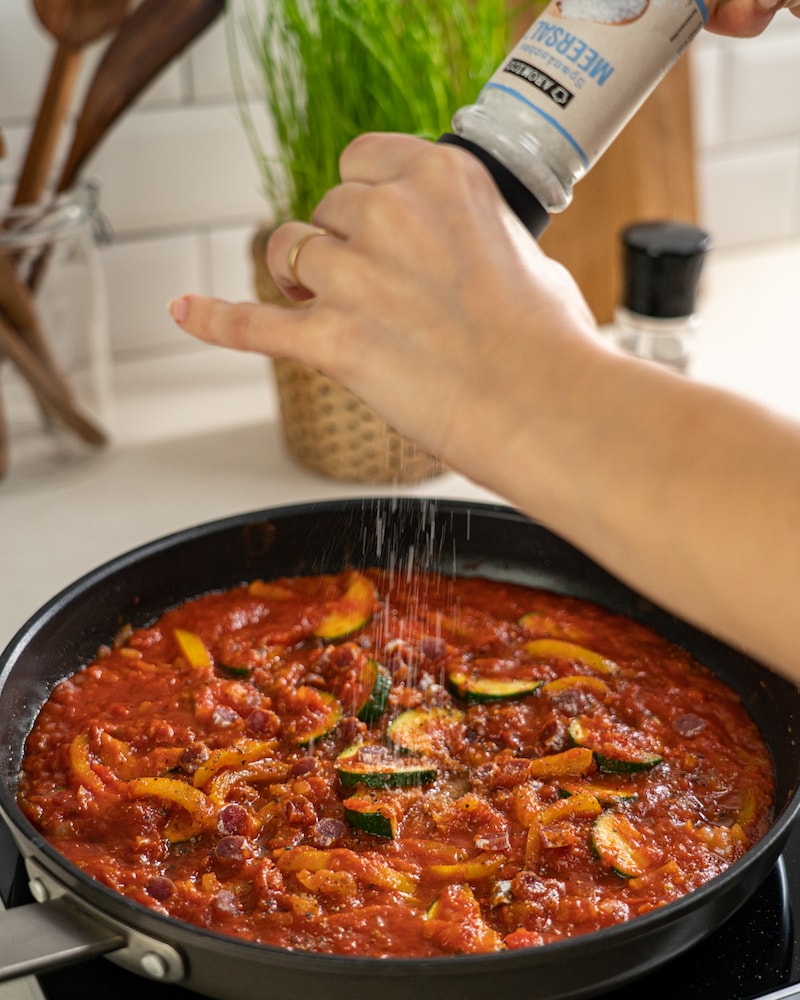 Auf diesem Bild siehst du wie die Spaghetti gewürzt wird.