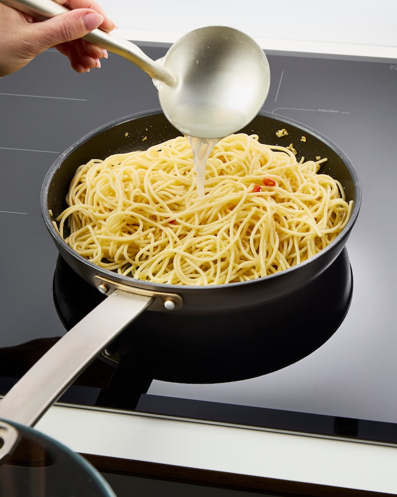 Dieses Bild das Nudelwasser zu den Spaghetti hinzugegeben wird.