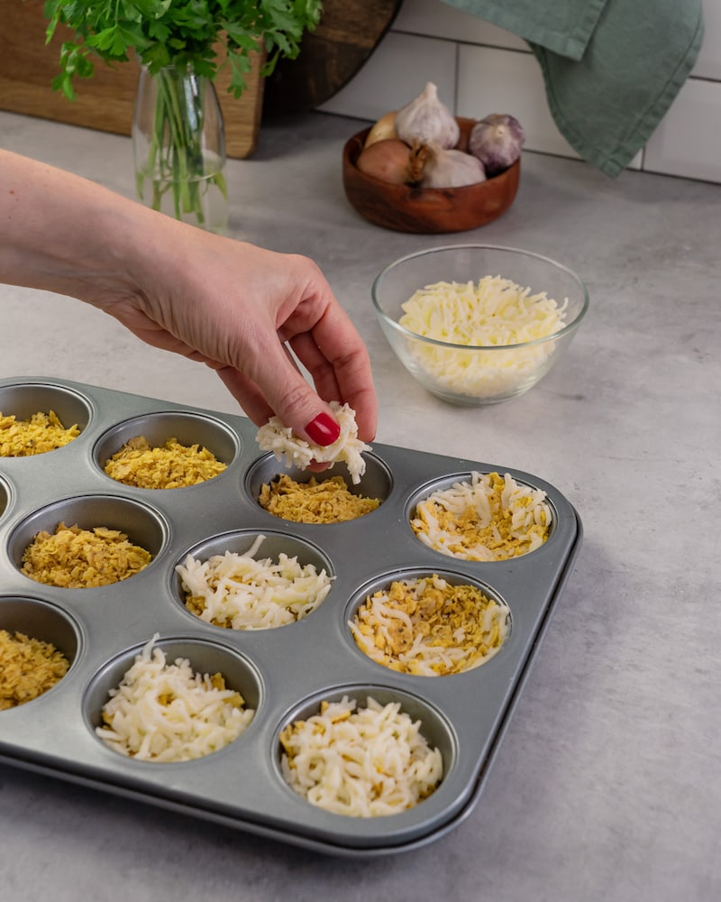 Dieses Bild zeigt die Cups mit Käse bestreut werden.