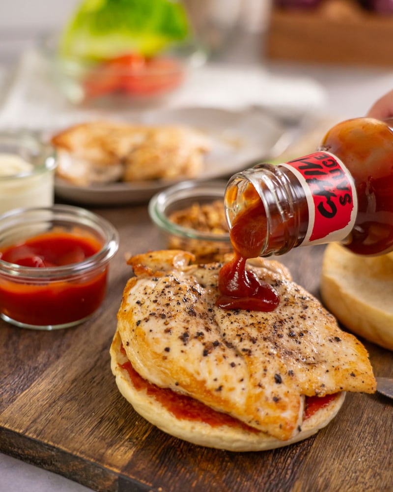 Dieses Bild zeigt wie die Sauce auf den Burger gegeben wird.
