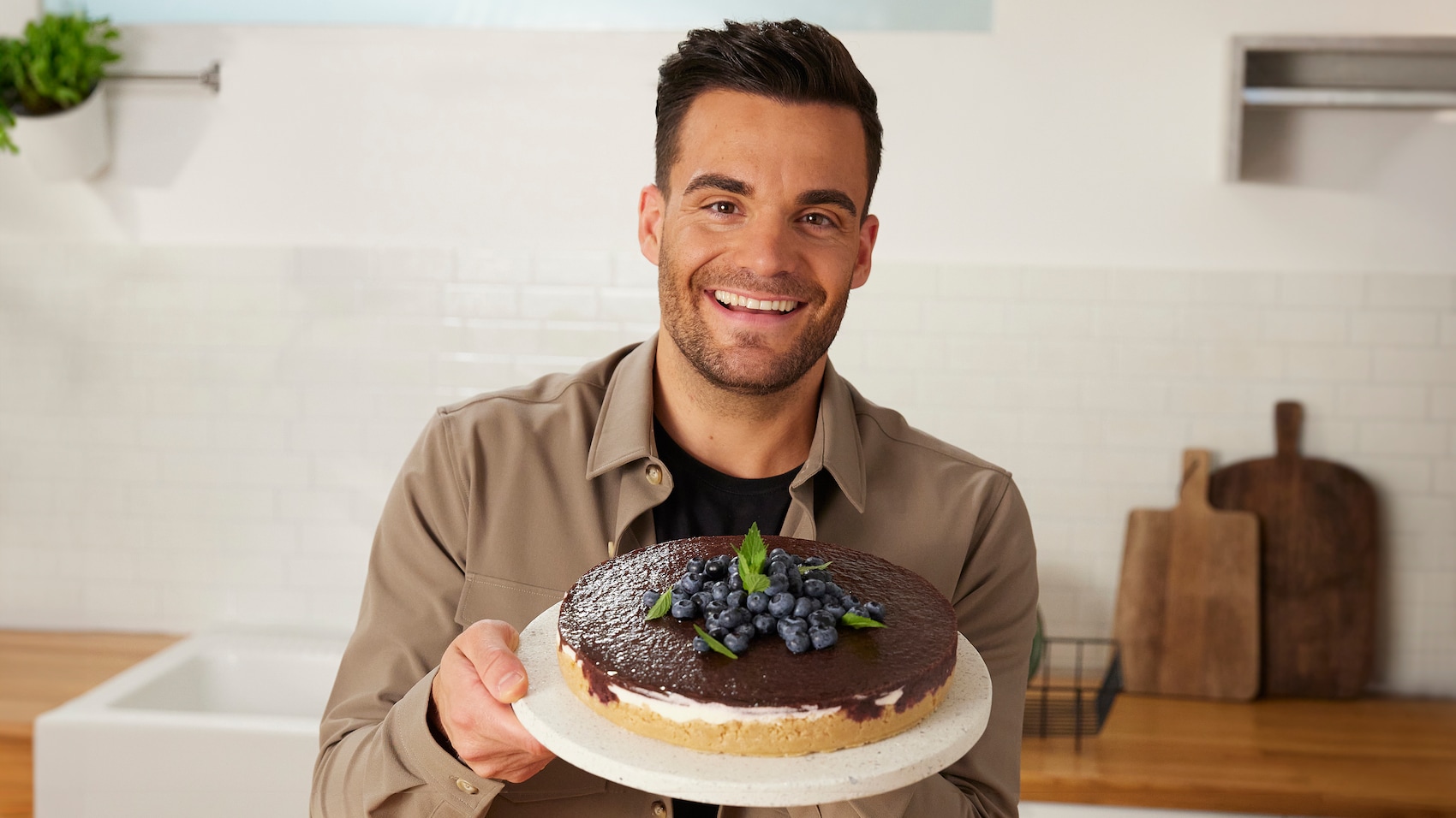 Stefano Zarrella hält eine Heidelbeertorte in die Kamera.