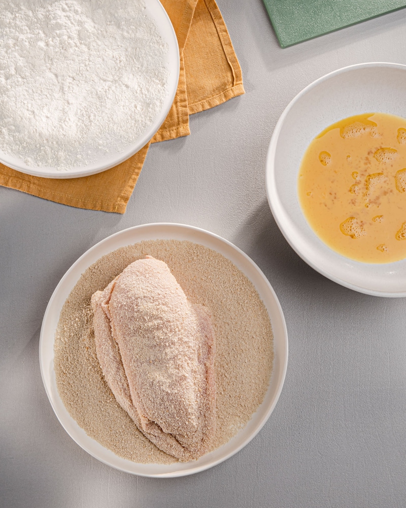 Dieses Bild zeigt, wie die Hähnchenbrust paniert wird.