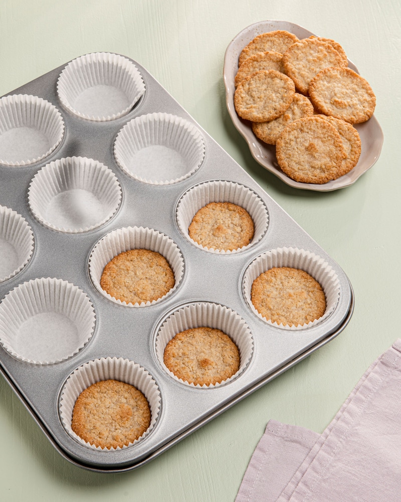 Dieses Bild zeigt wie die Kekse in Muffinförmchen ausgelegt werden.