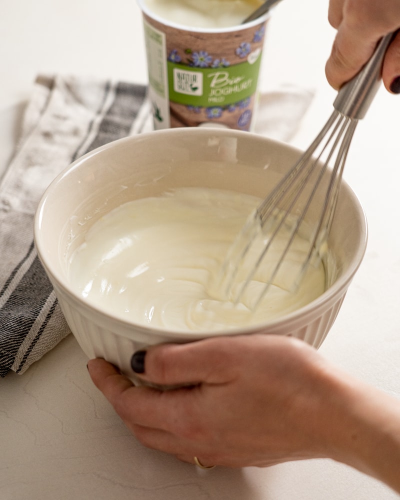 Auf diesem Bild siehst du wie Joghurt und Schmand verrührt werden.