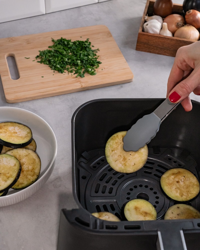Dieses Bild zeigt, wie die Aubergine in die Heißluftfritteuse gegeben wird.