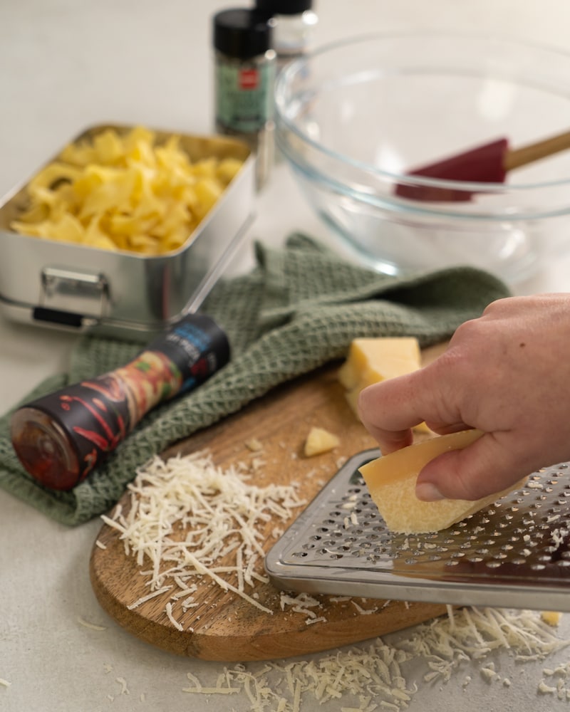 Auf diesem Bild siehst du wie Käse gerieben wird.