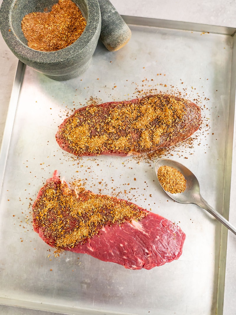 Dieses Bild zeigt wie Steaks gewürzt werden.