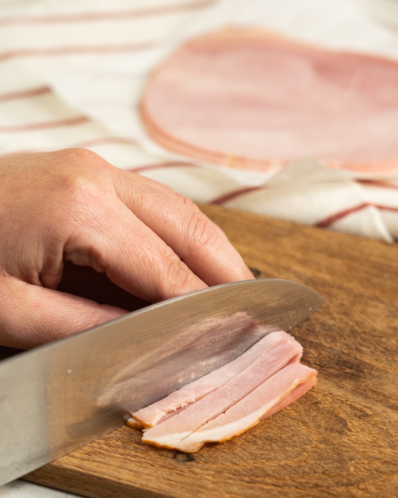 Auf diesem Bild siehst du wie Kochschinken geschnitten wird.
