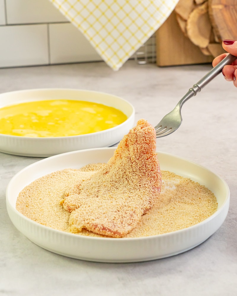 Dieses Bild zeigt wie das Putenschnitzel im Paniermehl gewälzt wird.