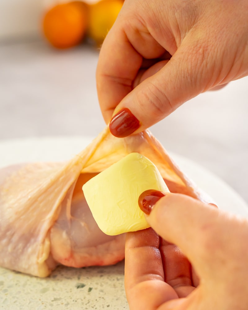 Dieses Bild zeigt wie die Butter unter das Hähnchen gegeben wird.