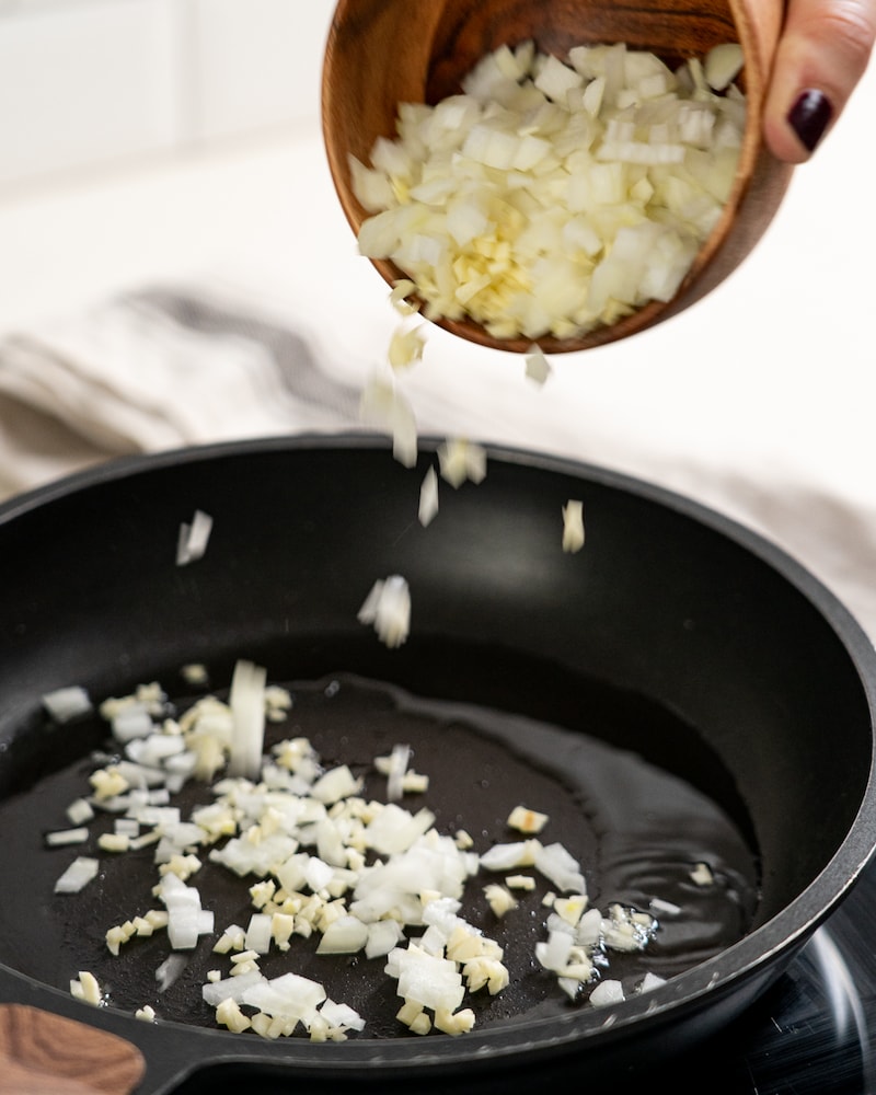 Auf diesem Bild siehst du wie Zwiebeln und Knoblauch angebraten wird.