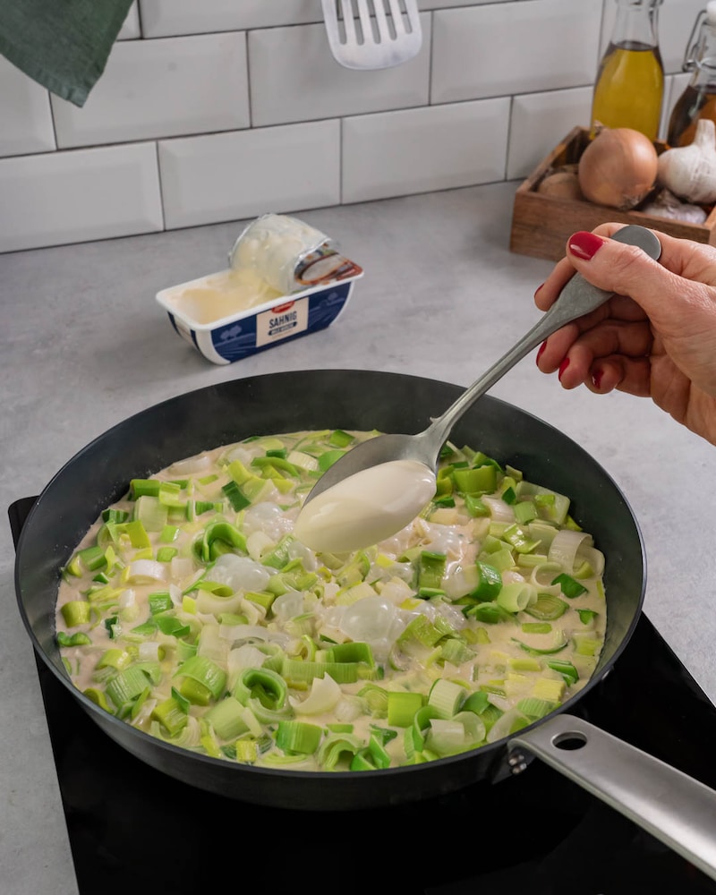 Dieses Bild zeigt, wie Schmelzkäse hinzugegeben wird.