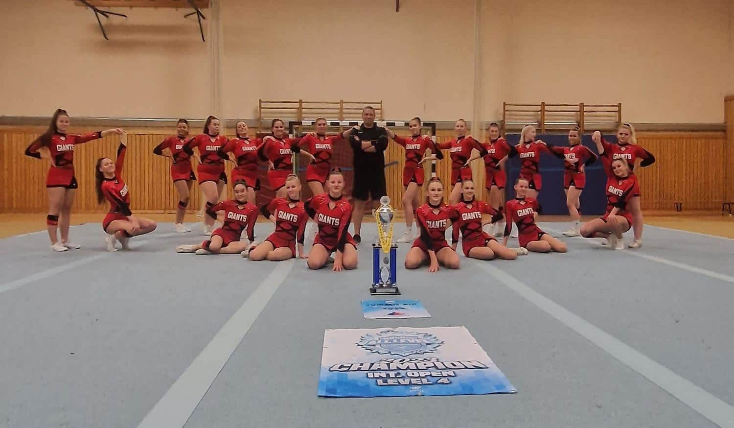 Cheerleader nehmen stolz ihre Gruppenaufstellung ein neben ihrem gewonnen Pokal 