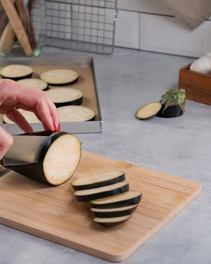 Dieses Bild zeigt wie die Auberginen in Scheiben geschnitten werden.