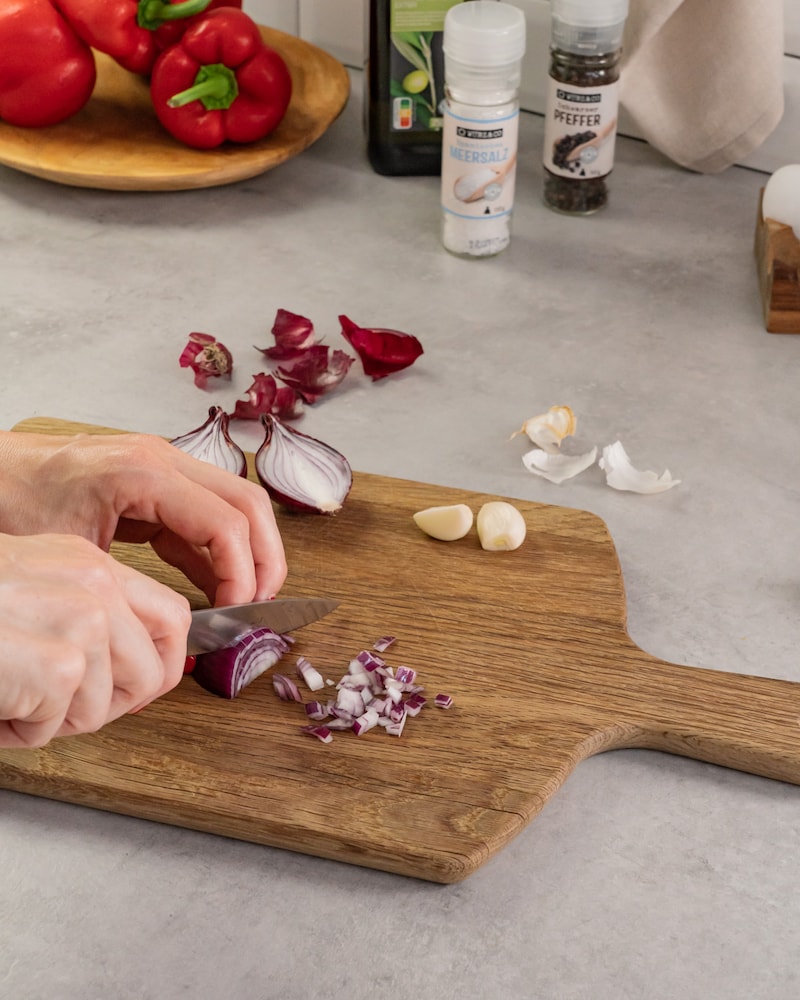 Dieses Bild zeigt wie die Zwiebeln und der Knoblauch geschnitten wird.