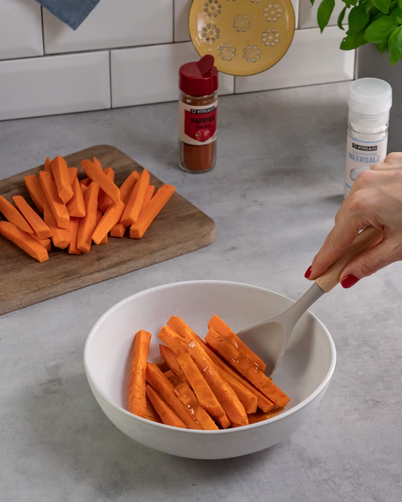 Dieses Bild zeigt, wie die Süßkartoffelstäbchen mariniert werden.