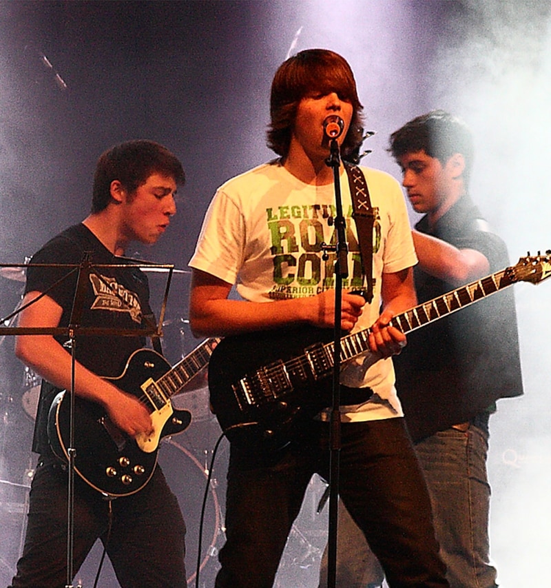 Jugendliche spielen als Band auf Bühne