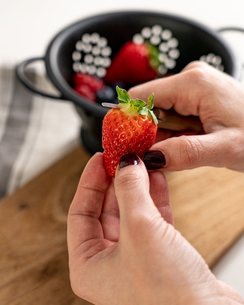 Auf diesem Bild siehst du wie von Erdbeeren der Strunk entfernt wird.