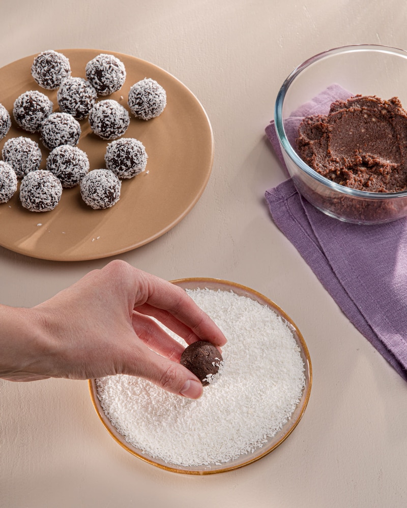 Dieses Bild zeigt, wie die Balls in den Kokosflocken gewälzt werden.